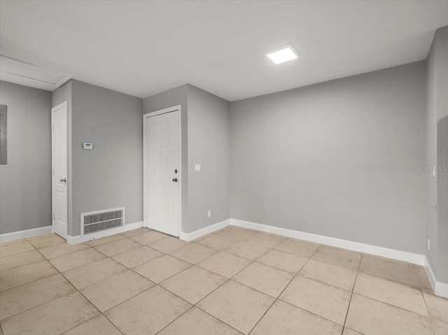 spare room with light tile patterned floors, visible vents, electric panel, and baseboards