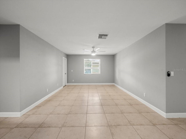 spare room featuring light tile patterned flooring, ceiling fan, and baseboards