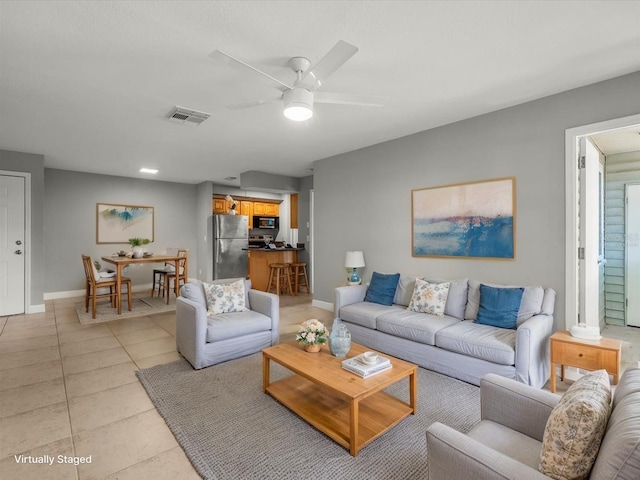 living area featuring baseboards, visible vents, light tile patterned floors, and ceiling fan