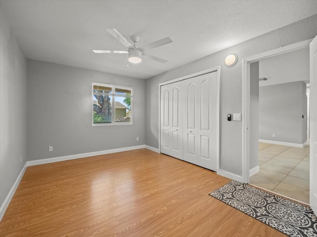 unfurnished bedroom with a ceiling fan, light wood finished floors, baseboards, and a closet
