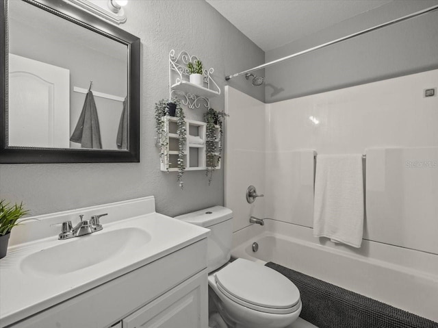 full bathroom with toilet, a textured wall, vanity, and bathtub / shower combination