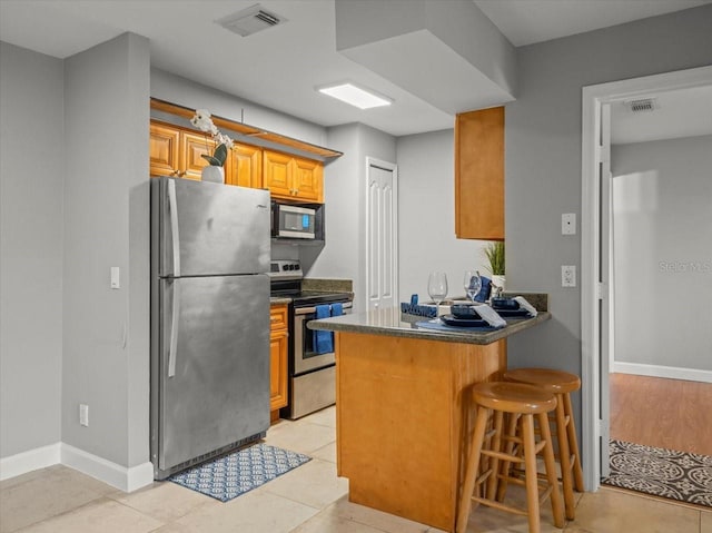 kitchen with a breakfast bar, visible vents, a peninsula, and appliances with stainless steel finishes