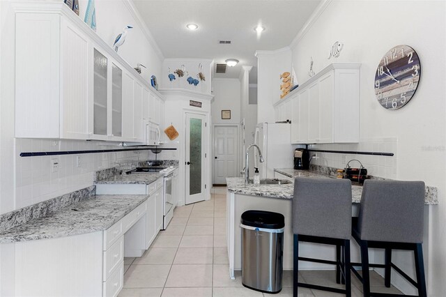 kitchen with white cabinetry, light stone countertops, white appliances, and ornamental molding