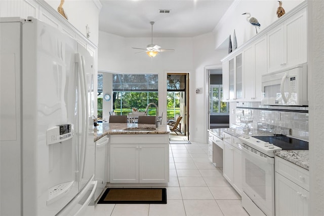 kitchen featuring white cabinetry, sink, light stone counters, and white appliances