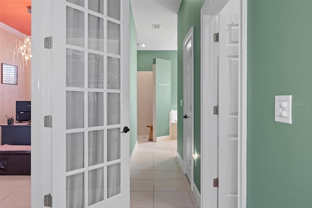 hallway featuring light tile patterned flooring, ornamental molding, a textured ceiling, and a chandelier