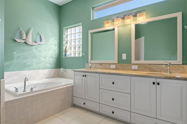 bathroom featuring tile patterned flooring, vanity, and tiled bath