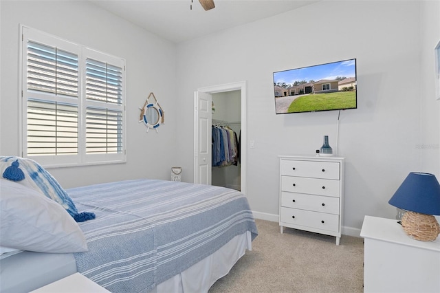 carpeted bedroom featuring a walk in closet, ceiling fan, and a closet