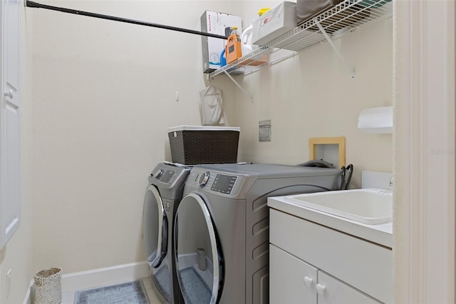 clothes washing area with washer and clothes dryer, tile patterned flooring, cabinets, and sink