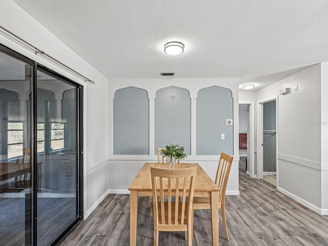 dining space with hardwood / wood-style flooring and a textured ceiling