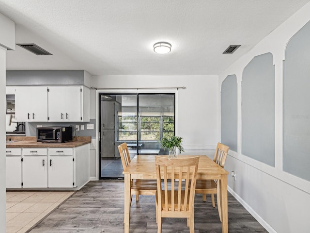 dining area with a textured ceiling and light hardwood / wood-style flooring