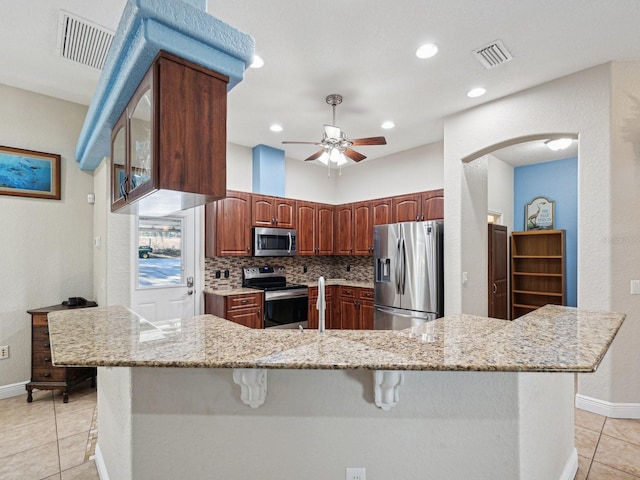 kitchen with decorative backsplash, light tile patterned flooring, light stone countertops, and appliances with stainless steel finishes