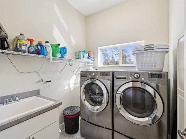 laundry room featuring light tile patterned flooring, washer and dryer, and sink