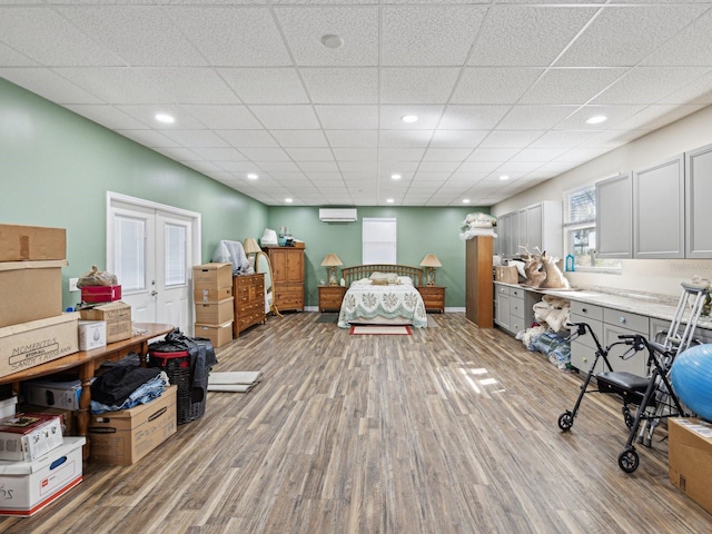 bedroom featuring a paneled ceiling, a wall mounted air conditioner, and hardwood / wood-style floors