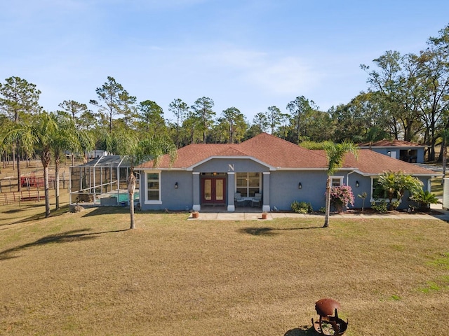 view of front of house featuring a front yard, glass enclosure, and a patio area