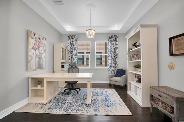 office space with a tray ceiling, dark hardwood / wood-style flooring, and a notable chandelier