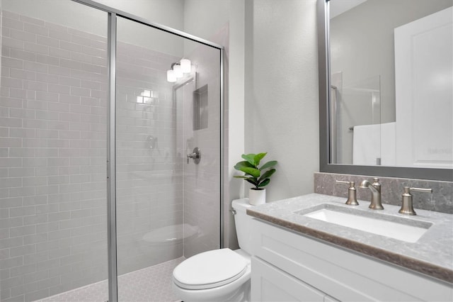 bathroom featuring vanity, a shower with shower door, and toilet