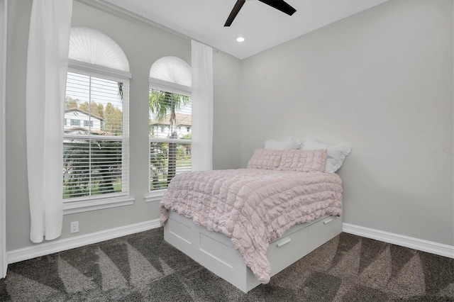 bedroom with multiple windows, ceiling fan, and dark colored carpet