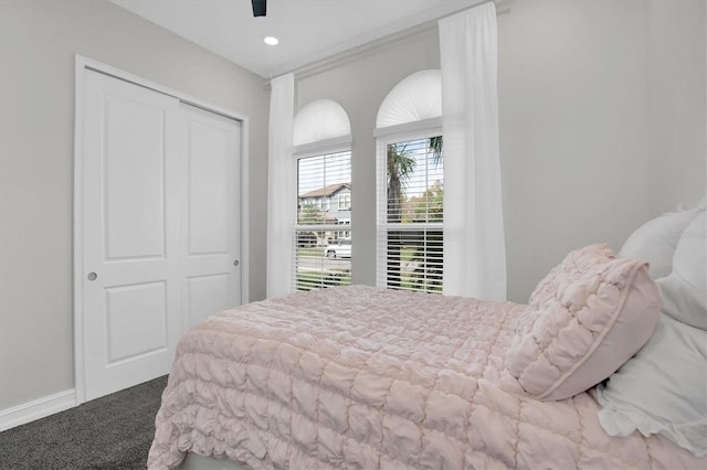 carpeted bedroom with ceiling fan and a closet