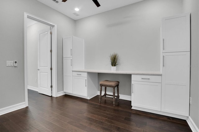 unfurnished office featuring ceiling fan, dark hardwood / wood-style flooring, and built in desk