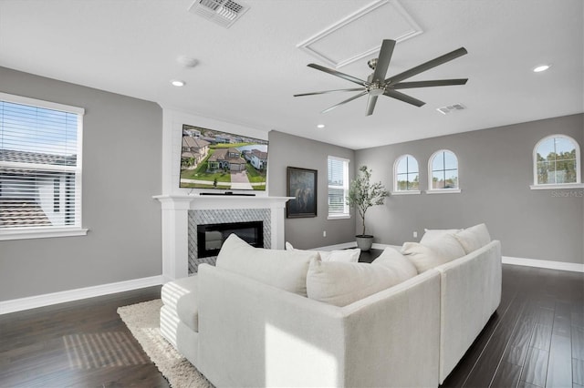 living room featuring dark hardwood / wood-style floors, ceiling fan, and a tiled fireplace