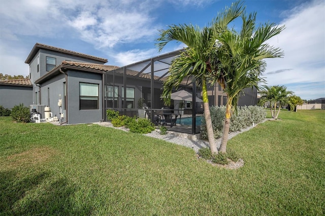 back of property featuring a lawn, glass enclosure, and a patio area