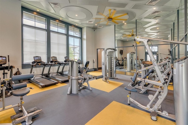 exercise room featuring ceiling fan, a towering ceiling, and coffered ceiling