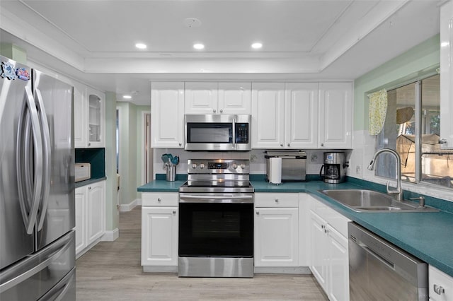 kitchen with sink, light hardwood / wood-style flooring, decorative backsplash, white cabinetry, and stainless steel appliances