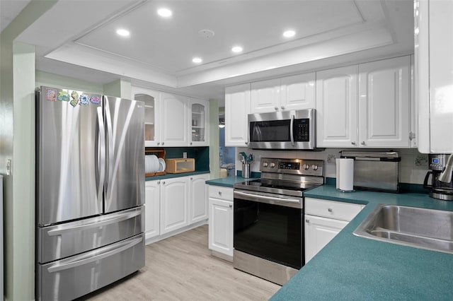 kitchen featuring appliances with stainless steel finishes, white cabinetry, and a raised ceiling