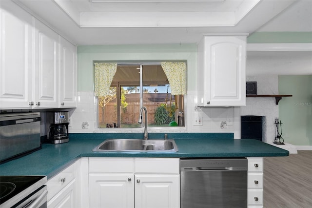 kitchen with dishwasher, sink, decorative backsplash, white cabinetry, and wood-type flooring