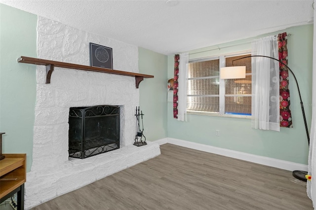 unfurnished living room with a stone fireplace, wood-type flooring, and a textured ceiling