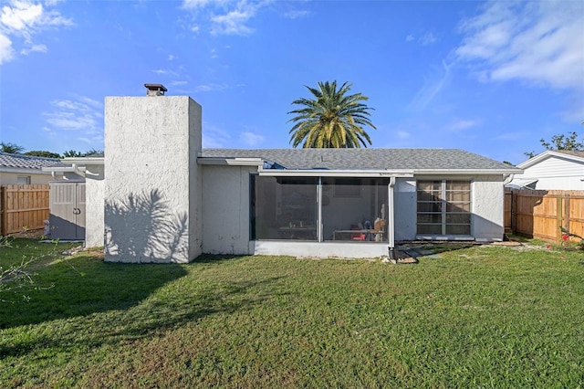 rear view of property with a yard and a sunroom