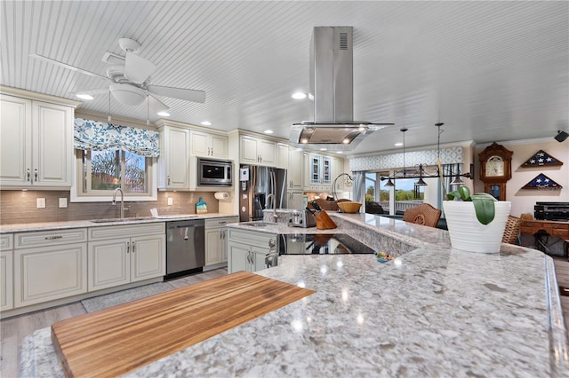 kitchen with sink, light hardwood / wood-style flooring, appliances with stainless steel finishes, decorative light fixtures, and island range hood