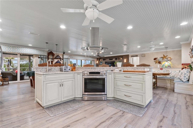 kitchen with pendant lighting, light hardwood / wood-style floors, electric stove, and a kitchen island with sink