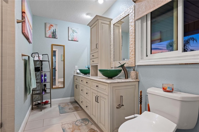 bathroom with tile patterned flooring, vanity, a textured ceiling, and toilet