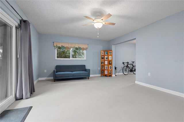 sitting room featuring a textured ceiling, concrete floors, and ceiling fan