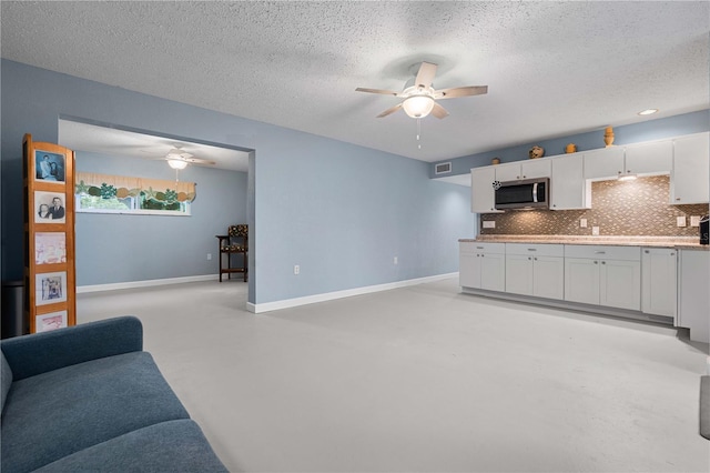 living room with ceiling fan and a textured ceiling