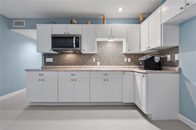 kitchen with white cabinets, backsplash, and a textured ceiling