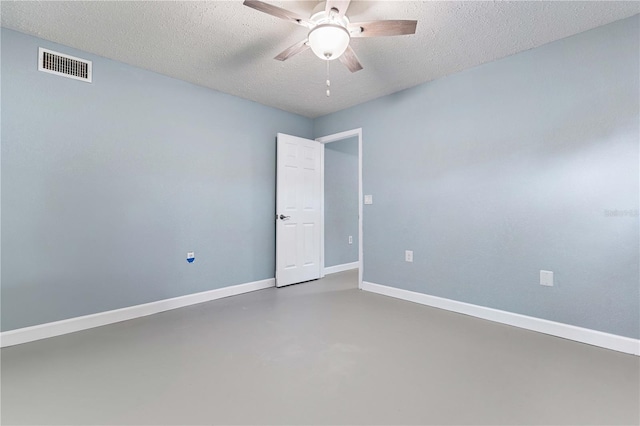 spare room with ceiling fan, a textured ceiling, and concrete floors