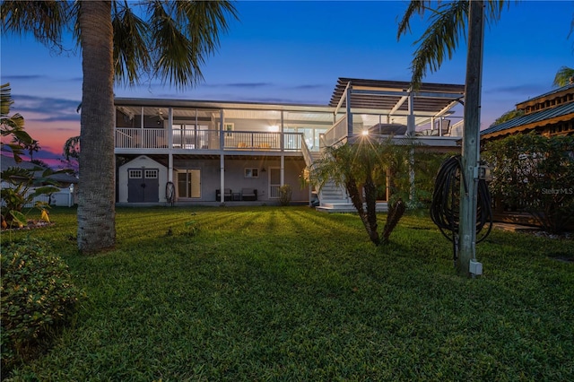 back house at dusk with a yard and a wooden deck