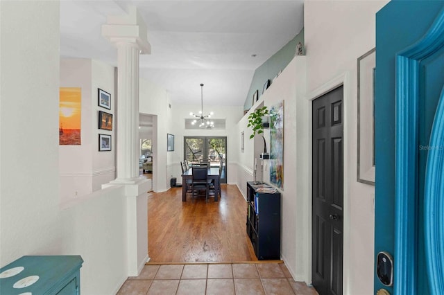 hall with decorative columns, a chandelier, vaulted ceiling, and light wood-type flooring