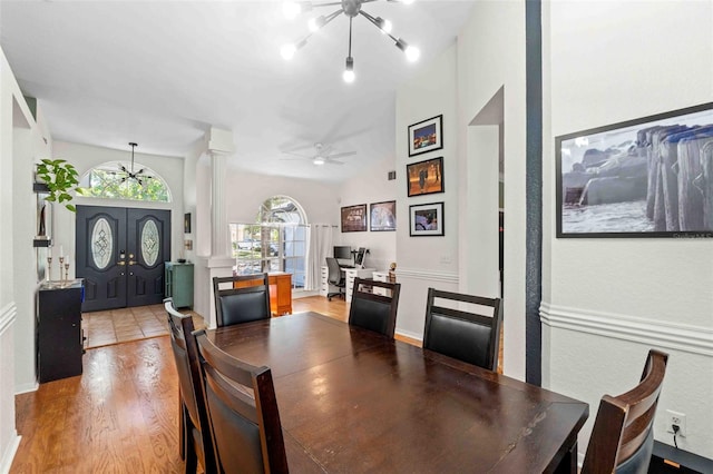 dining space with lofted ceiling, an inviting chandelier, french doors, and light hardwood / wood-style flooring