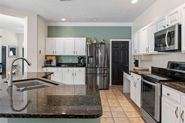 kitchen with white cabinetry, sink, stainless steel appliances, dark stone counters, and a kitchen island with sink