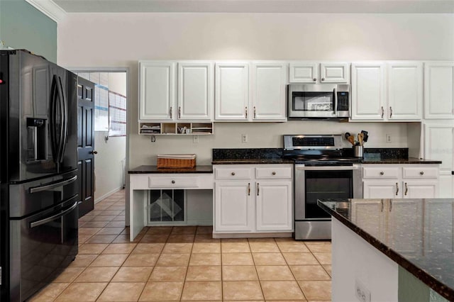 kitchen featuring appliances with stainless steel finishes, ornamental molding, dark stone counters, light tile patterned floors, and white cabinetry