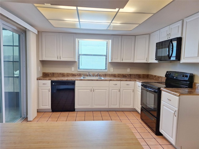 kitchen with light tile patterned flooring, sink, white cabinetry, and black appliances