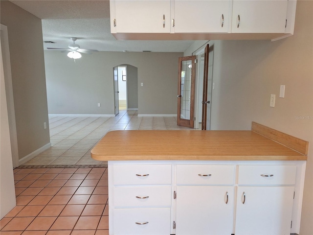 kitchen featuring kitchen peninsula, ceiling fan, light tile patterned floors, a textured ceiling, and white cabinetry