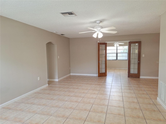 spare room with ceiling fan, french doors, light tile patterned floors, and a textured ceiling