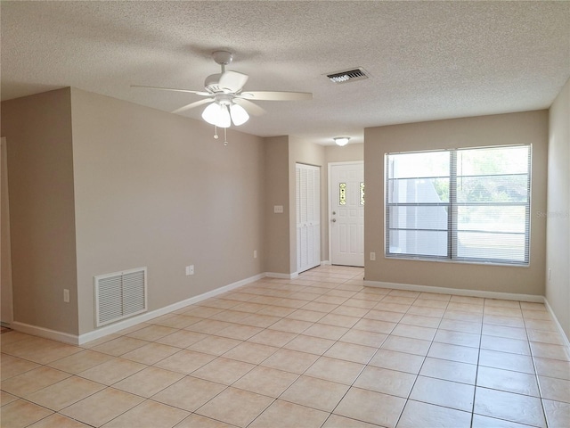 tiled spare room with ceiling fan and a textured ceiling