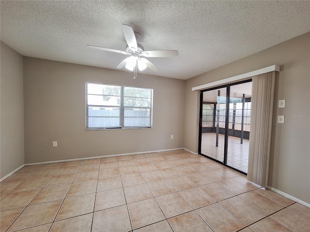 empty room with ceiling fan, light tile patterned floors, and a textured ceiling