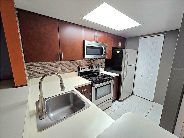 kitchen featuring light tile patterned floors, backsplash, stainless steel appliances, and sink