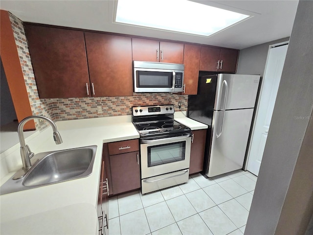 kitchen featuring backsplash, sink, light tile patterned floors, and stainless steel appliances